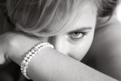 Young woman luring from behind her arm with pearl bracelet